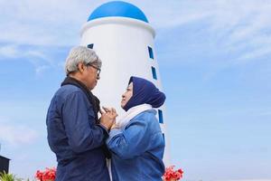 romantiska äldre par inför varandra och håller hand med blå himmel bakgrund. foto