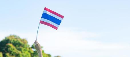 hand som håller thailands flagga på naturbakgrund. thailändska nationsdagen och farsdagen koncept foto