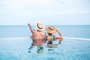 lyckligt par i infinitypool på lyxhotell mot havet., njut av i tropisk resort. avkopplande, sommar, resor, semester, semester, romantik och helgkoncept foto