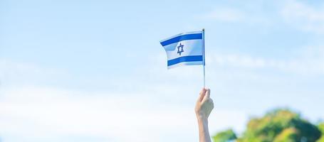 hand som håller Israels flagga på naturbakgrund. Israels självständighetsdag och glada festkoncept foto