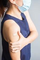 kvinna visar sin arm med bandage efter att ha fått covid 19-vaccin. vaccination, flockimmunitet, biverkningar, vaccineffektivitet och coronaviruspandemi foto