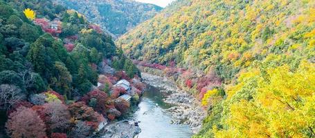 färgglada lövberg och katsurafloden i arashiyama, landskapslandmärke och populärt för turistattraktioner i Kyoto, Japan. höst höstsäsong, semester, semester och sightseeing koncept foto