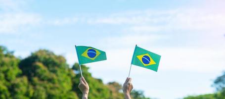 hand som håller Brasiliens flagga på blå himmel bakgrund. september självständighetsdag och glada festkoncept foto