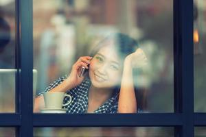 asien leende kvinna prata telefon på café och njuta av kaffe