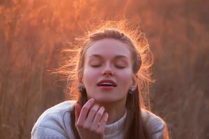 vacker ung blond kvinna dagdrömmar vid solnedgången foto