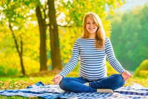 glad gravid kvinna kopplar av på gräsmattan i parken foto