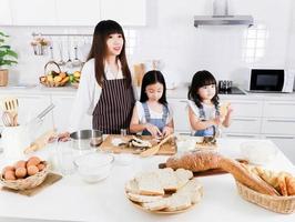 porträtt av liten asiatisk flicka och mamma förbereder bakning matlagning i köket foto