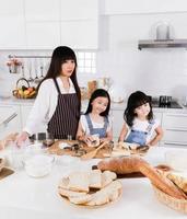 lycklig kärleksfull familj förbereder bageri tillsammans. mor och barn dotter flicka agerar inlägg och leende i köket foto