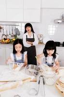 lycklig familj två barn förbereda en baka med mamma i köket foto
