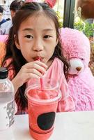 Asien liten flicka dricka vattenmelon smoothie foto
