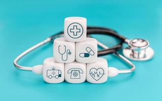 sjukförsäkring koncept. medicinska symboler på kubformade block och stetoskop på blå bakgrund foto