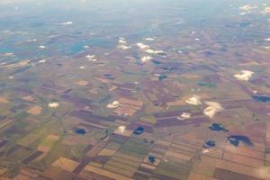 flygfoto över jordbruksmark. utsikt från planet till marken. kvadrater av fält under molnen foto
