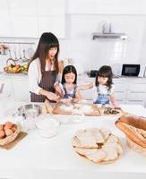 familjens matlagningstid glad mamma och två dather hjälper till att laga mat baka tillsammans i köket hemma foto