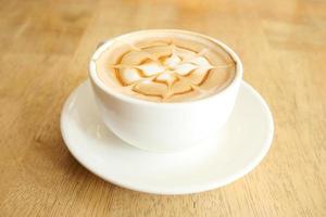 en kopp sent kaffe med blommönster på toppen på caféet foto