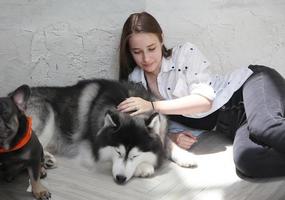 flicka husdjursägare kramar med hundvalp. glad mänsklig kvinnlig och söt rolig hund liggande på golvet tillsammans foto