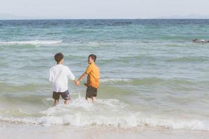 homosexuella porträtt ungt asiatiskt par springer med glada tillsammans på stranden på sommaren, asien gay turism för fritid och koppla av med lycka i semestern till sjöss, hbt juridiskt koncept. foto