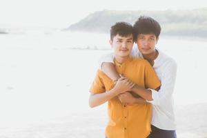 homosexuella porträtt ungt asiatiskt par står kram tillsammans på stranden på sommaren, asien gay turism för fritid och koppla av med romantisk och lycka i semestern till sjöss, hbt-koncept. foto