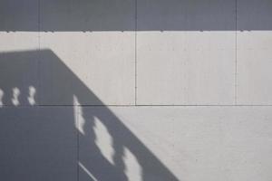 solljus och balkongskugga på ytan av grå gipsväggbakgrund foto