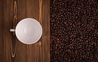 rostade kaffebönor och kaffekopp på trästruktur. ovanifrån bruna kaffebönor konsistens för bakgrund och tapeter foto