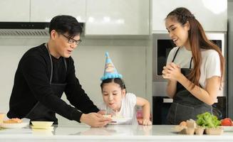 nya generationens asiatiska familj lagar mat tillsammans och organiserar en liten födelsedagsfest för vår lilla dotter i husets kök foto