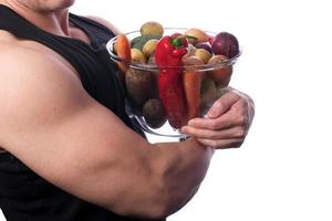 muskulös man som håller frukt och grönsaker foto