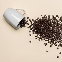 kaffebönor och vit kopp på färgad bakgrund foto