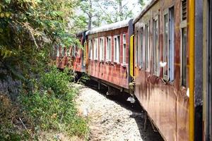 leksakståg rör sig på bergssluttningar, vacker utsikt, ena sidan berg, ena sidan dalen rör sig på järnväg till kullen, bland grön naturskog. leksakståg från kalka till shimla i Indien foto