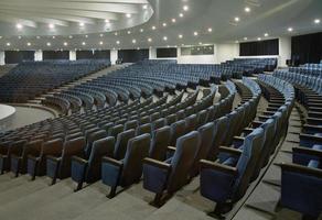 ett stort auditorium med flera rader med blå stolar
