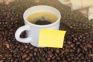 gul klisterlapp på en kopp kaffe och kaffebönor bakgrund. foto