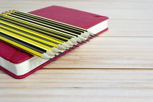 trä 2b pennor liggande på röd anteckningsbok på träbord. kopieringsutrymme. foto