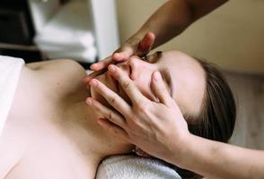 massör gör massage på en kvinnas ansikte på spa. begreppet kosmetiska ingrepp. foto