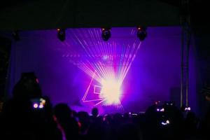 lila laser neonstrålar. folkmassa som tittar på lasershow på gatufestival. foto