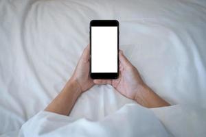 kvinna som håller på sin smartphone medan hon sover i sängen bakgrund. foto