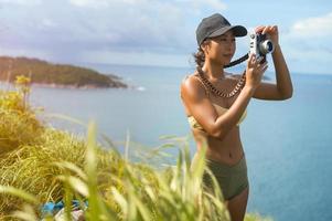 vacker asiatisk kvinna i sportkläder som tar foto på bergstoppen vid havet efter vandring, resor och ekoturismkoncept.