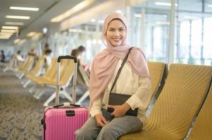 ung kvinnlig muslimsk resenär som bär resväskor på den internationella flygplatsen, resor, semester och resa koncept. foto