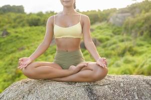 vacker asiatisk kvinna i sportkläder gör yoga på bergstoppen vid havet efter vandring, resor och meditationskoncept. foto