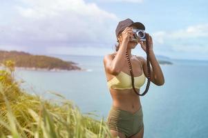 vacker asiatisk kvinna i sportkläder som tar foto på bergstoppen vid havet efter vandring, resor och ekoturismkoncept.