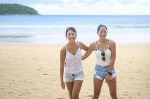 två attraktiva kvinnliga vänner njuter och kopplar av på stranden, sommar, semester, semester, livsstilskoncept. foto