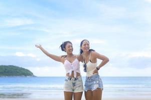 två attraktiva kvinnliga vänner njuter och kopplar av på stranden, sommar, semester, semester, livsstilskoncept. foto