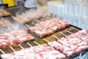 grillade fyrkantiga nötkött pinnar japanska är ordnade på den stora pan tallrik med rök runt. foto