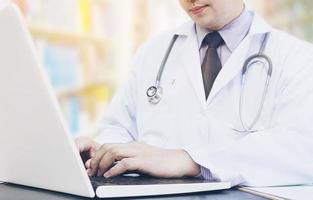 manlig läkare arbetar med laptop i sin klinik foto