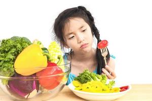 asiatisk härlig flicka visar tråkigt uttryck med färska färgglada grönsaker isolerade över vit bakgrund foto