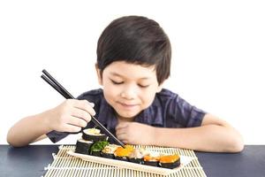 asiatisk härlig pojke äter sushi över vit bakgrund foto