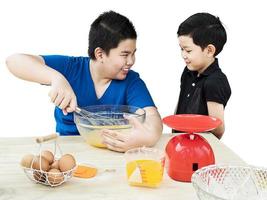barn gör gärna en tårta isolerade över vita. fotot är fokuserat på den äldre pojkens hand. foto