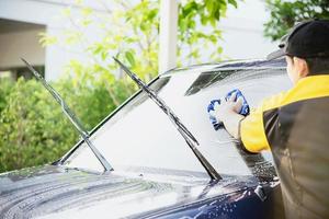man tvättar bil med schampo - vardagsliv bilvårdskoncept foto