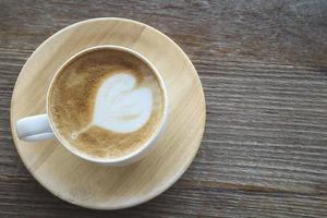 vintage varm kaffekopp med fin latte art dekoration på gamla trä textur bord foto