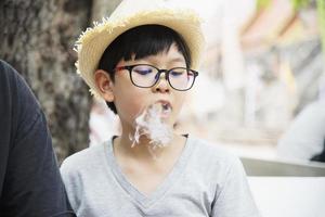 Asiatisk pojke som äter röka canny glatt - människor och snack lycklig tid koncept foto