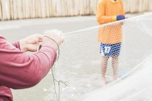 fiskare släpper ut fisk från sin trål på en strand foto