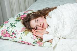 flicka sover i en vit säng hemma. ung kvinna sover i nattkläder på det vita linnet i sängen hemma, ovanifrån. foto