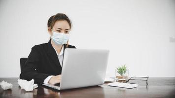 sjuk ung asiatisk affärskvinna som bär skyddande ansiktsmask foto